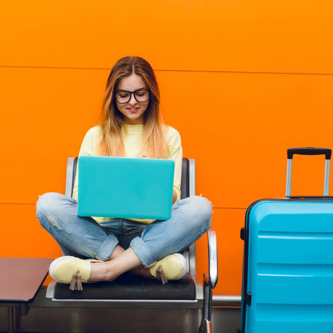 Young Girl With Long Hair Is Sitting Chair Orange Background She Wears Yellow Sweater Jeans She Is Typing Laptop